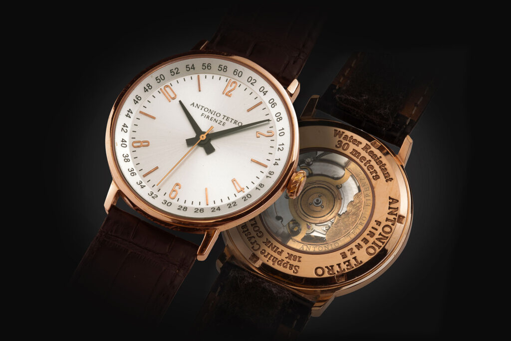 An 18k pink gold watch showing the white dial face and the open exhibition case back revealing its mechanical movement