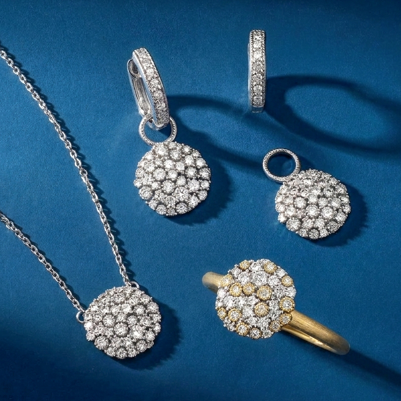 White gold pavé diamond cluster necklace, drop earrings, disc charm, and matching yellow gold textured ring on light blue