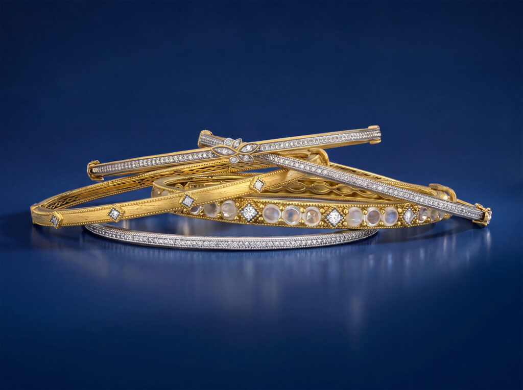 Overlapping stack of textured yellow gold and platinum bangle bracelets set with pavé diamonds