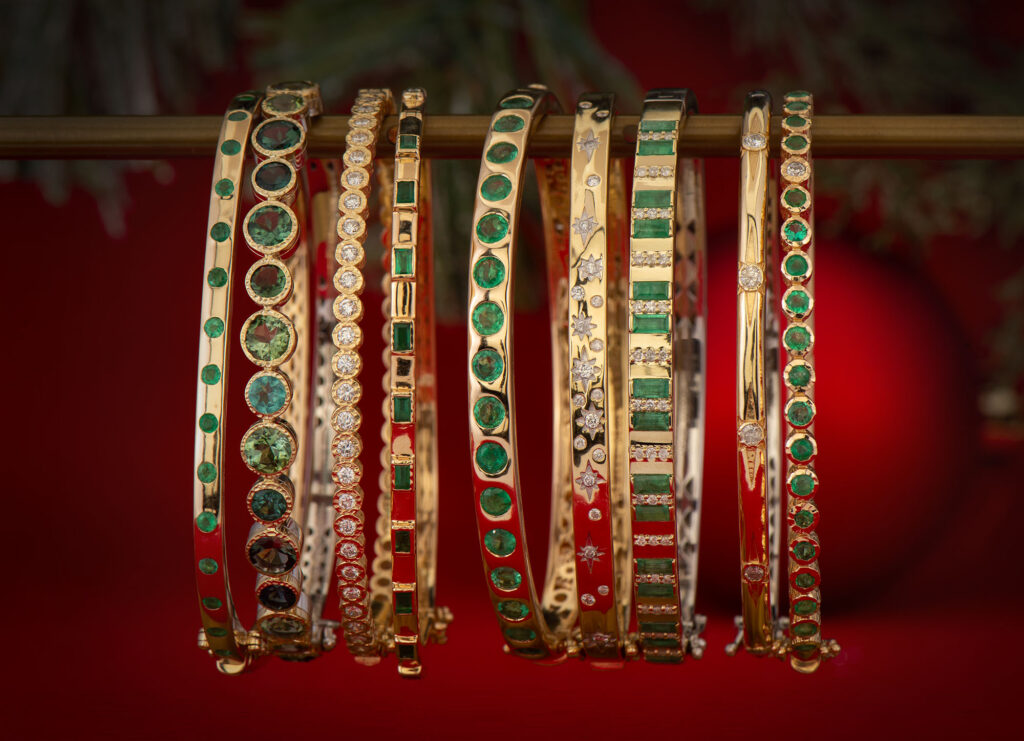 Yellow gold bangle bracelets set with baguette emeralds, green tourmaline, and pavé diamond starbursts