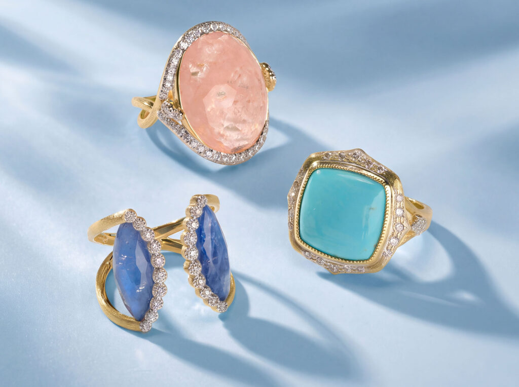 Three yellow gold cocktail rings featuring an oval rose quartz, cushion-cut turquoise, and blue sapphires