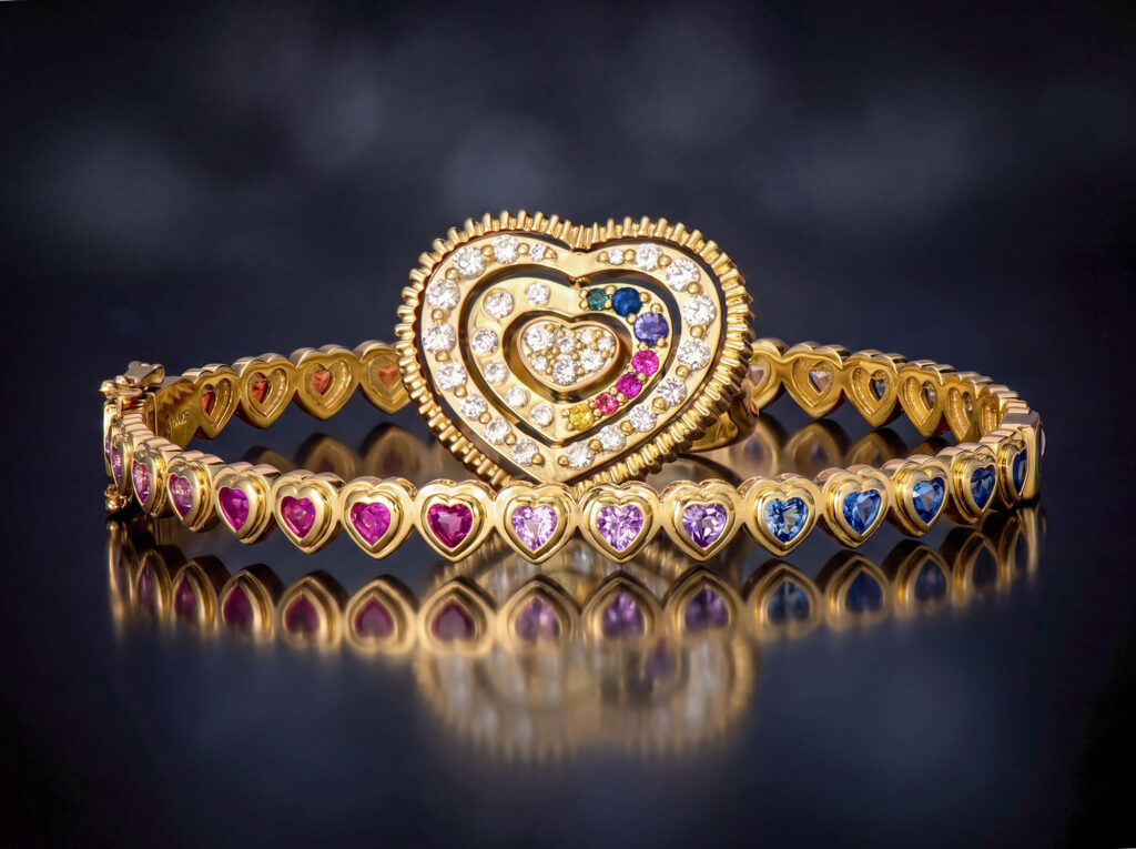 Yellow gold heart-shaped ring and bracelet set with a gradient of pink, purple, and blue sapphires