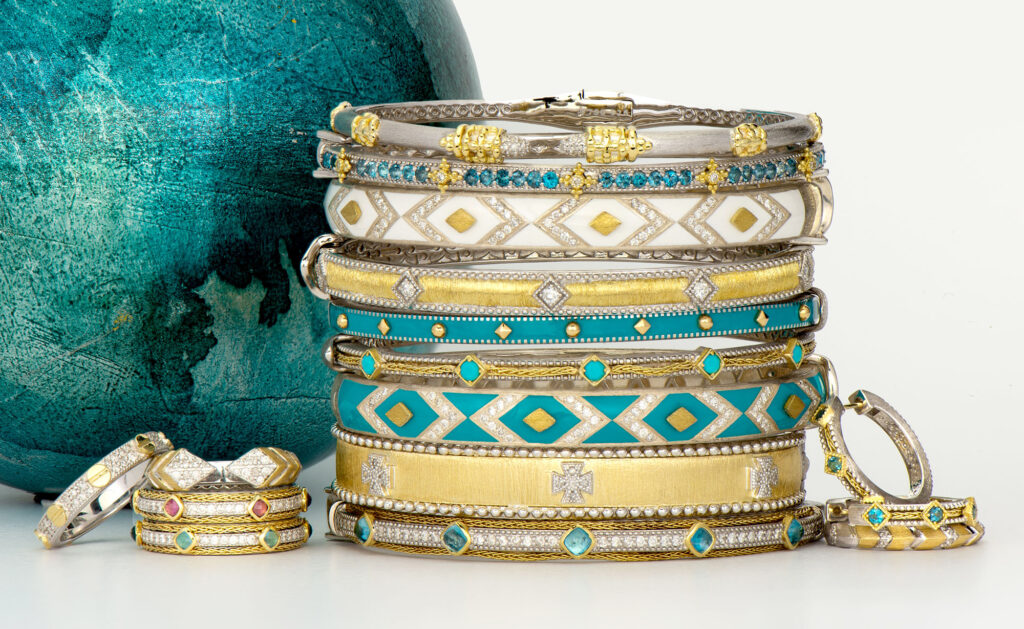 Precise stack of diamond, turquoise, and gold textured artisan bracelets next to a blue globe